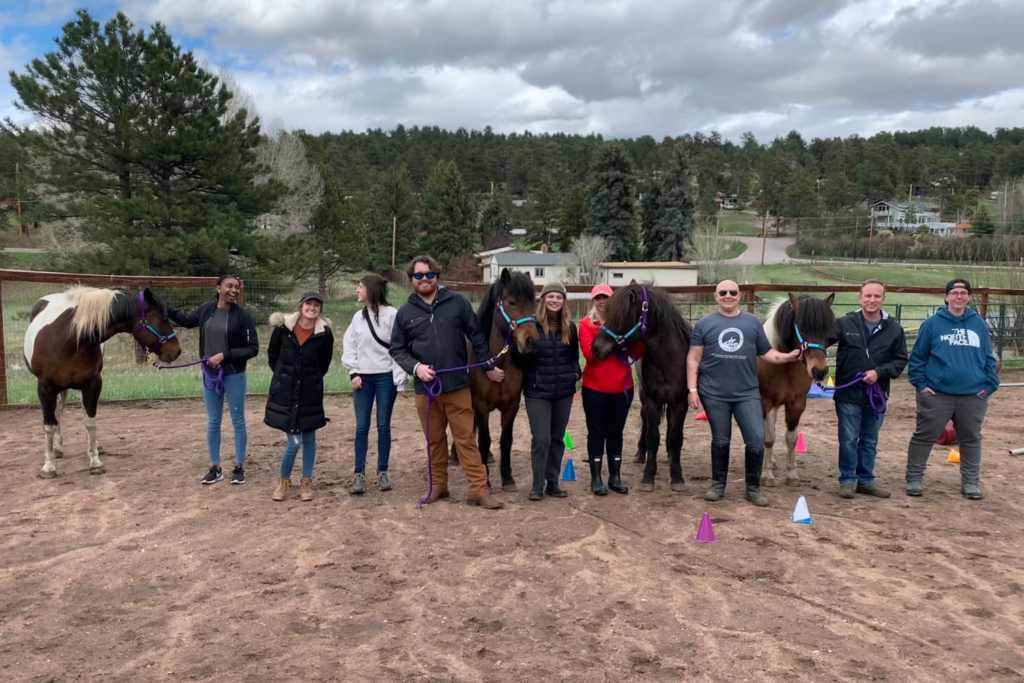 A group of people posting for a photo with horses